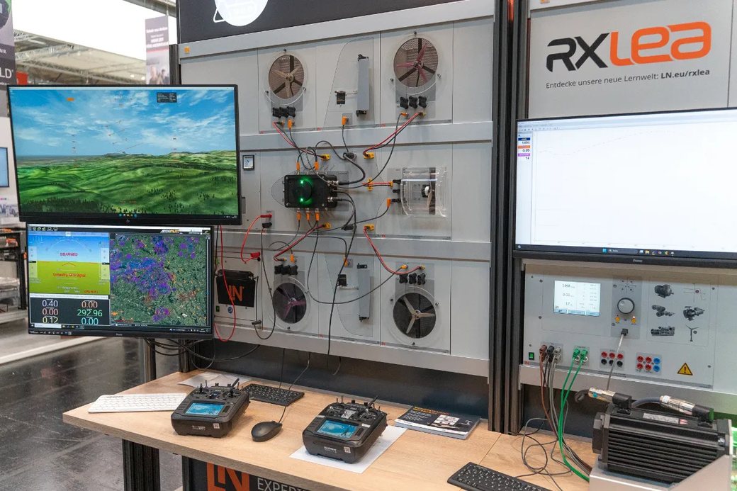 Drohnen-Lernsystem am Messestand: Trainingswand mit verkabelten Modulen, Simulator und Fernsteuerungen