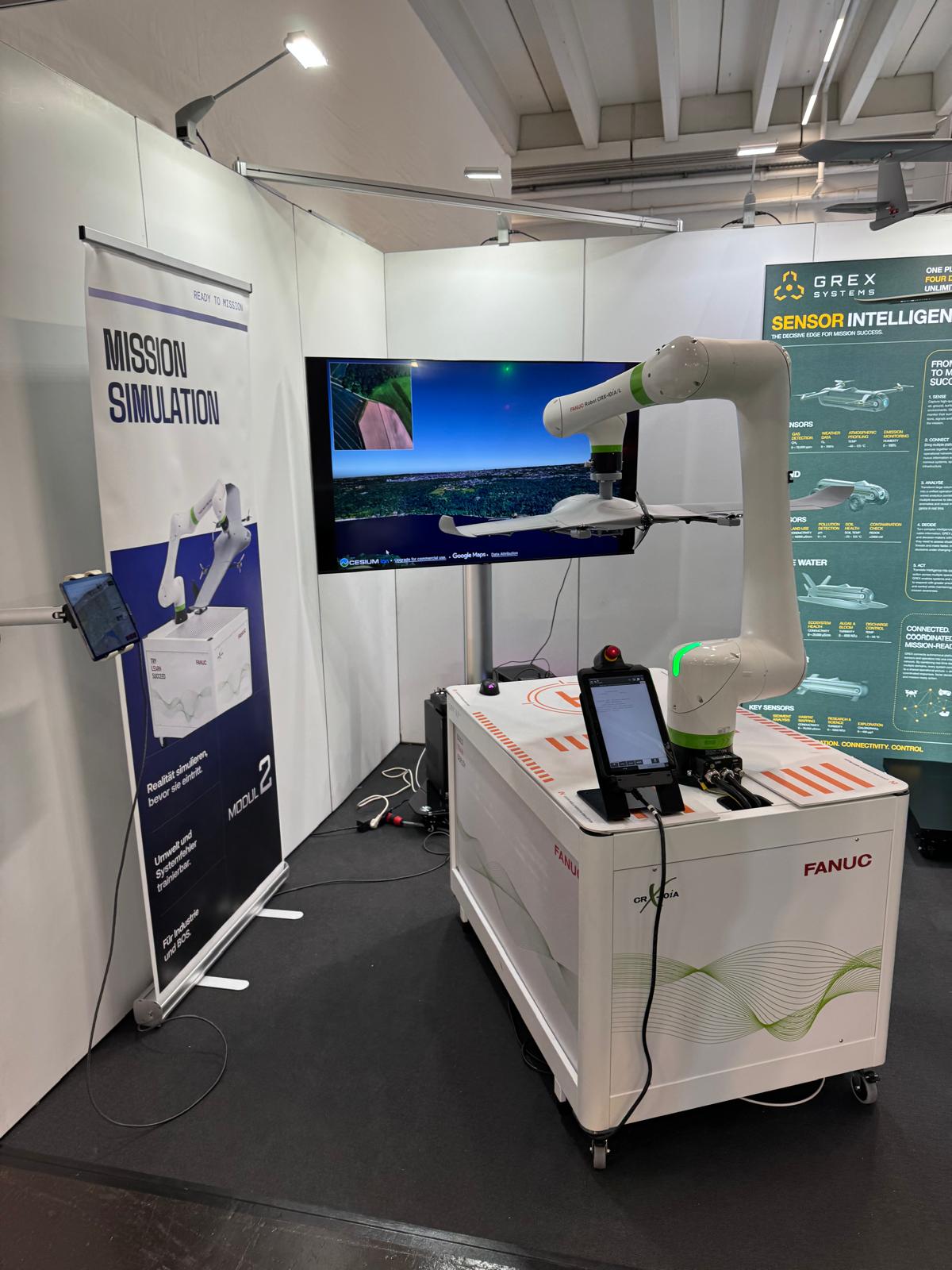 Mission-Simulation am GREX-Stand: Roboterarm mit Drohne vor einem Bildschirm mit Flugsimulation